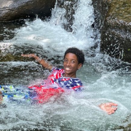 SIS student boy in stream in camp